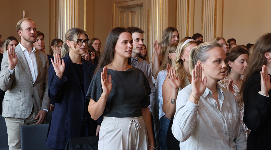 Gruppe junger Erwachsener steht in einem Saal und hebt die rechte Hand zum Schwur